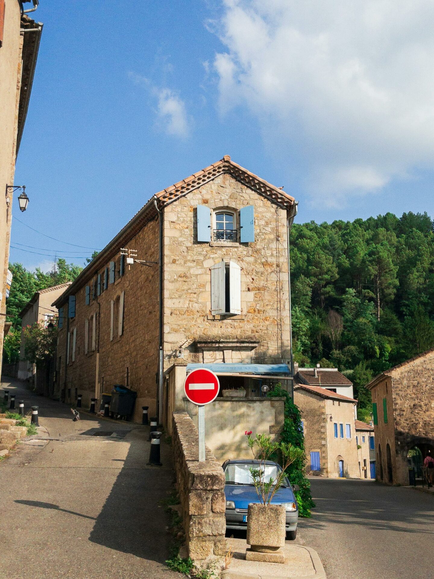 Quaint stone townhouse on a sunlit street in Saint-Etiénne, France.